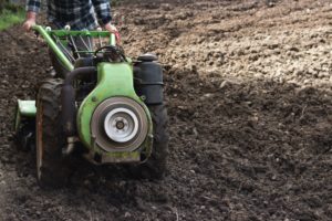 Person tilling lawn with equipment