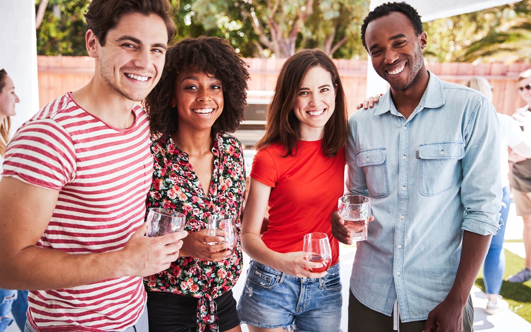 four people smiling holding a drink